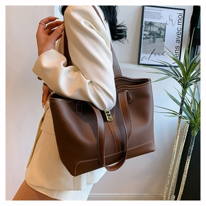 Detail of dark brown lychee grain leather tote bag with white contrast stitching and H-lock
