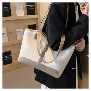 Close-up of white pebble leather tote bag with gold twist lock and beige trim detailing