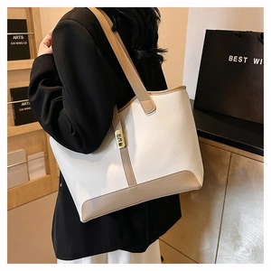 Litchi pattern leather tote bag in white and khaki shown on model in warm indoor setting