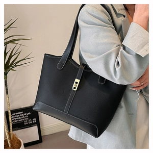 Detail of black pebbled leather tote bag with white contrast stitching and gold buckle
