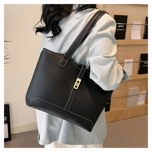 Detail of black pebbled leather tote bag featuring white stitching and gold hardware