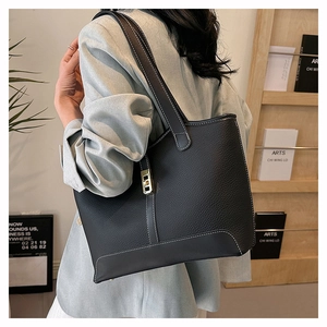 Detail of black pebbled leather tote with contrast stitching and gold lock buckle