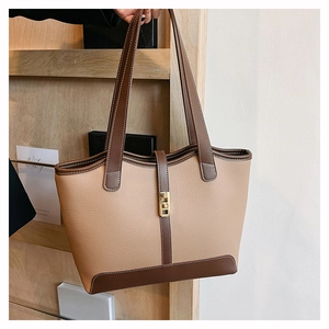 Close-up of dual-tone leather tote bag with lychee grain texture and golden metal lock