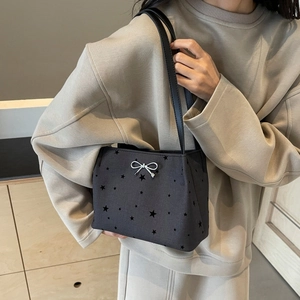Large black star-print bucket bag with a silver bow buckle worn by a model