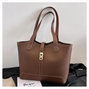 Close-up of brown litchi pattern leather tote bag with gold metal clasp and stitching