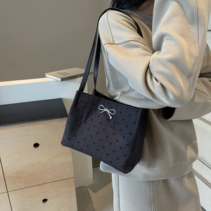 Chic black bucket bag with red heart pattern and silver bow detail worn by a model