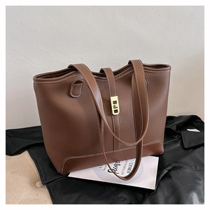 Detail of brown pebbled leather tote bag with contrast stitching and gold twist lock
