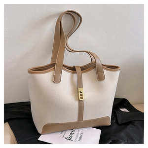 Detail of a white and tan tote bag with litchi texture and gold buckle on a black leather coat