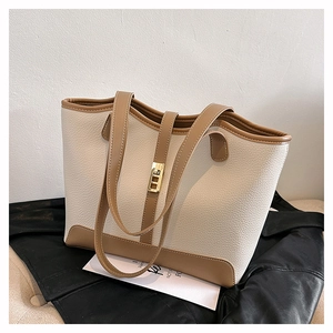 Detail of pebbled leather tote bag with contrast trim and gold metal buckle lock