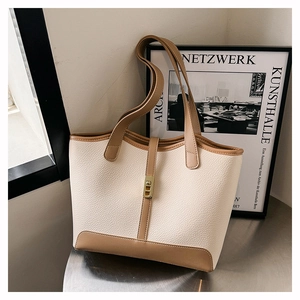 Close-up of beige and brown leather tote bag with metallic buckle in office setting