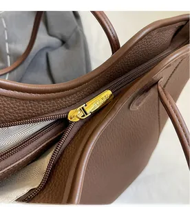 Detailed close-up of smooth gold zipper and textured brown lychee grain leather handbag