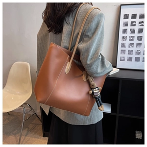 Sac cabas en cuir marron avec un charme lapin porté à l'épaule dans un intérieur