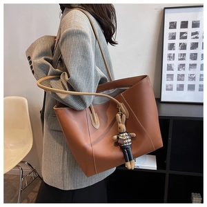 Détail d'un grand sac cabas en cuir PU marron avec coutures blanches et charme lapin