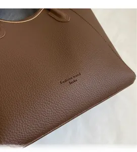 Close-up of brown lychee grain leather texture on tote bag with branding detail