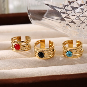 Detail of layered gold titanium rings set with red black and turquoise stones