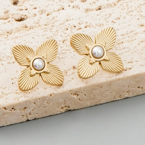 Golden flower stud earrings with pearl center on stone background, elegant floral jewelry