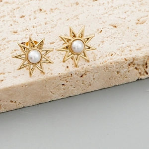 Golden sunflower stud earrings with central white pearls on a minimalist stone base