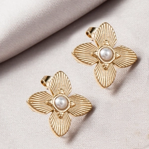 Detailed close-up of gold flower stud earrings with a pearl center and textured petals
