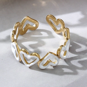 Dettaglio dell'anello a cuore traforato con smalto bianco e finitura dorata su tessuto
