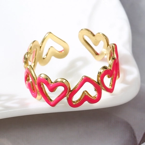 Dettaglio anello regolabile dorato con cuori in smalto rosa su vassoio di ceramica