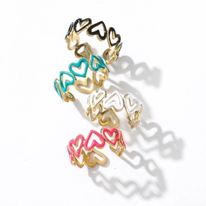 Dettaglio di anelli a cuore traforati in smalto colorato in nero, blu, bianco e rosa