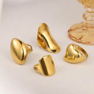 Set of four irregular gold rings with high-polish finish on a neutral textured surface