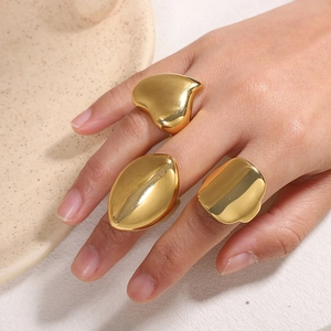 Close-up of three chunky gold liquid metal rings on a warm aesthetic ceramic tray