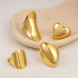 Macro view of four polished gold heart and lava style rings on a ceramic dish