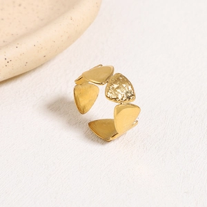 Irregular geometric gold open ring with matte and hammered texture on beige background