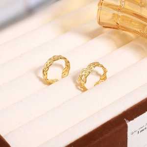 Detail of two gold adjustable rings with woven wheat and irregular wave textures