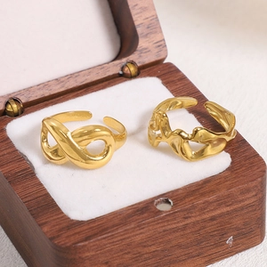 Detail of gold-plated infinity and irregular liquid metal texture open rings in a wooden box