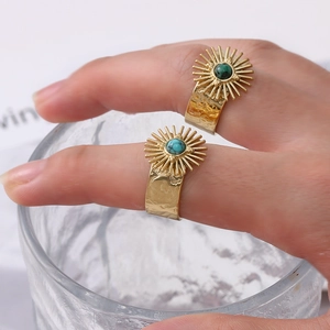 Detail of vintage gold sunburst rings with blue and green stones on model's hand