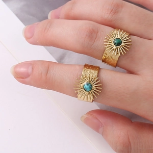 Close-up of retro gold-plated sunburst rings featuring turquoise stones and hammered texture