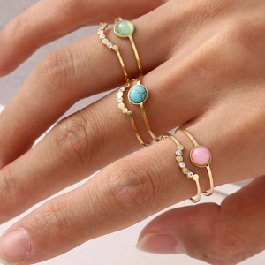 Close-up of bohemian gold rings set with natural stones and zirconia on fingers