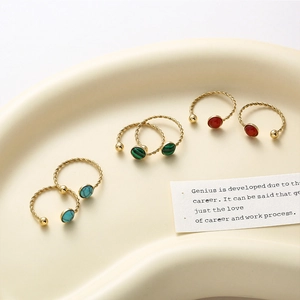 Macro detail of adjustable gold twisted rings featuring green, red, and blue gemstones