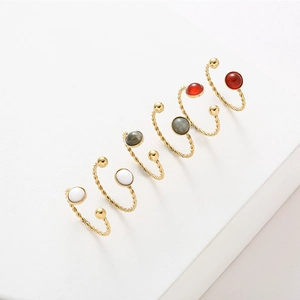 Detail of twisted gold stainless steel open rings with colorful natural stone inlays