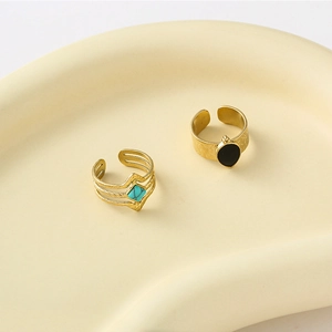 Vintage gold adjustable rings with turquoise and black stones on ceramic tray