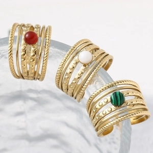Detail of three gold-plated multi-layer rings with red, white, and green gemstones