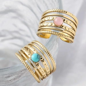 Close-up of gold layered rings with pink and turquoise natural stones on glass