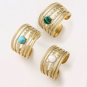 Detail of bohemian gold-plated tiered rings with round natural stones and textured bands