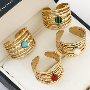 Close-up of stacked gold stainless steel rings with malachite and turquoise insets