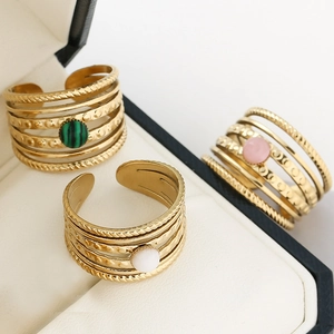 Detail of multi-layer gold plated rings with natural stone inlays on white leather