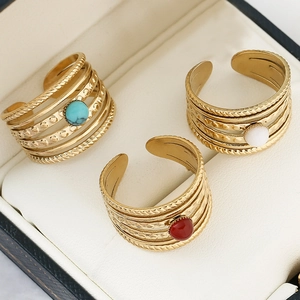 Detail of three gold multi-layer rings with turquoise, agate, and pearl in a jewelry box