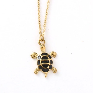 Détail du pendentif tortue en émail noir sur une chaîne délicate en acier doré