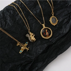 Détail de quatre colliers en acier inoxydable doré avec pendentifs écureuil et petit avion