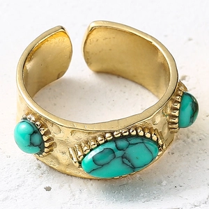 Détail macro d'une bague dorée texturée sertie de pierres turquoise style bohème