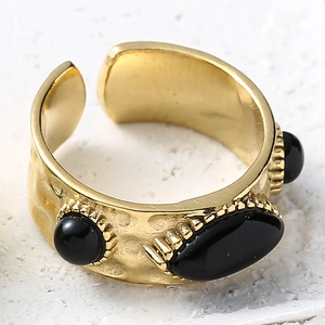 Détail de la bague dorée texturée avec pierres noires et artisanat de totem vintage
