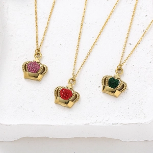 Detailed shot of crown necklaces with pink, red, and green cubic zirconia on stone stand