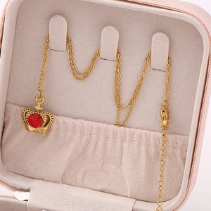 Close-up of golden crown pendant necklace with heart-shaped red micro-inlaid zircons
