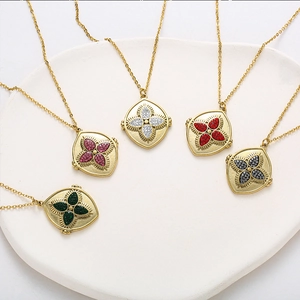 Détail de cinq pendentifs trèfle en or vintage avec zircons colorés sur un plateau